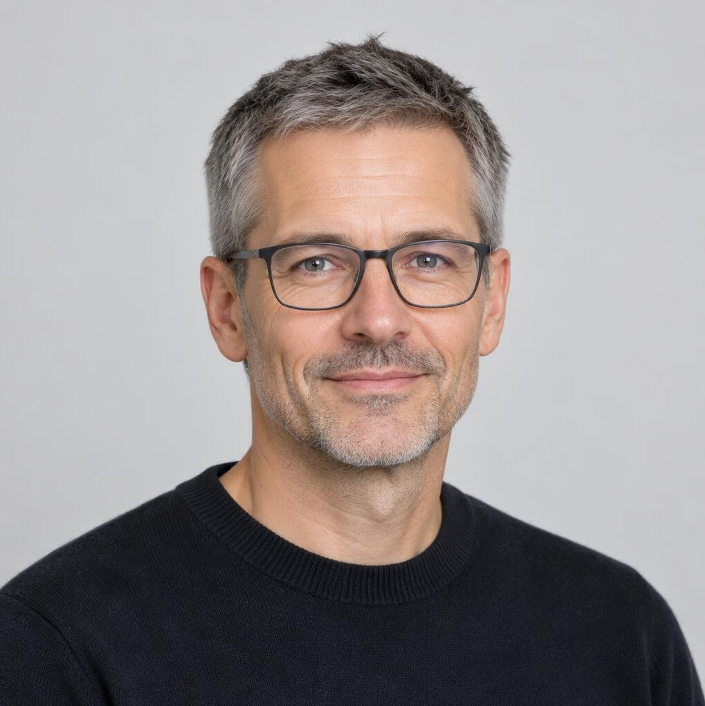 Studio portrait of a Swiss man in his forties with short hair and glasses